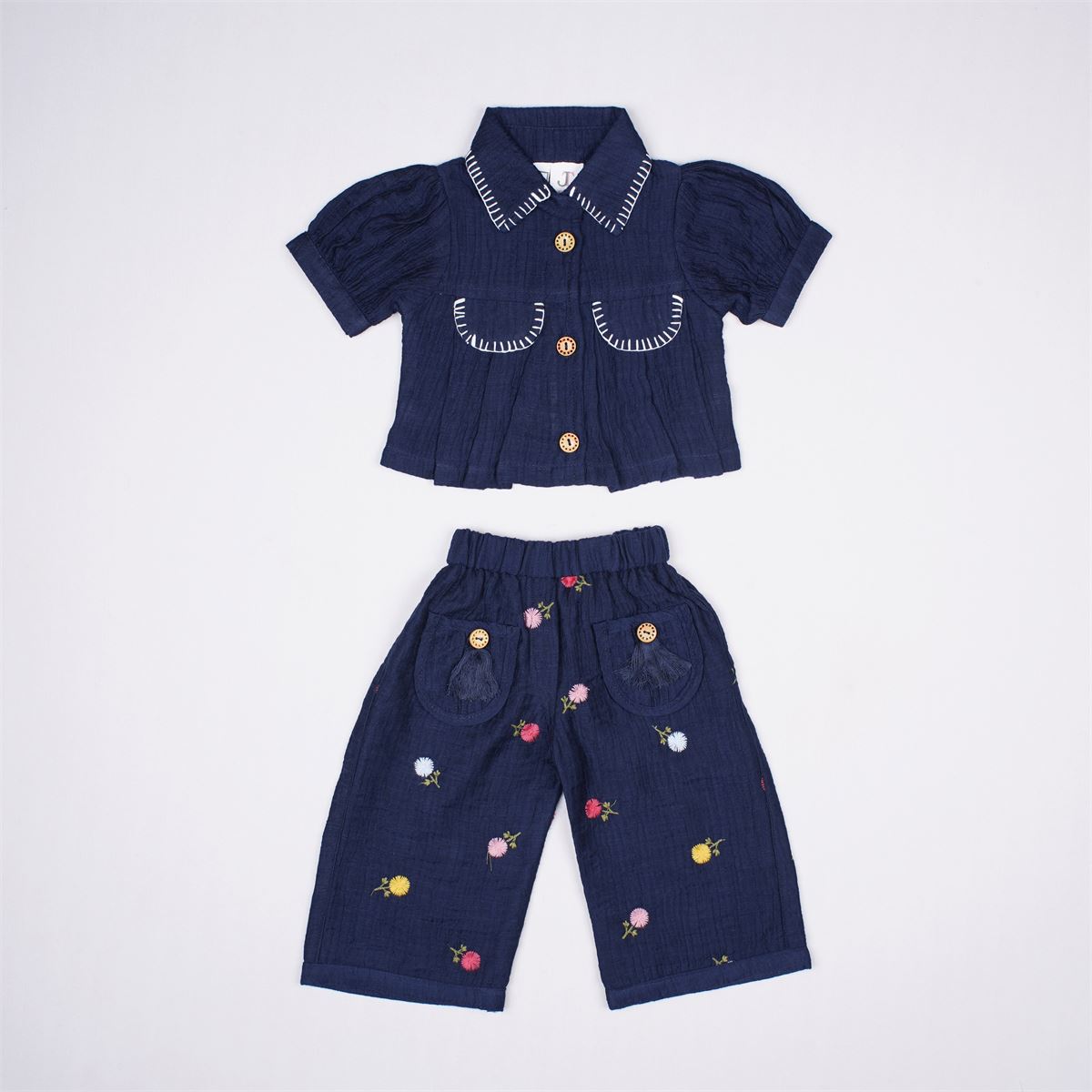 Justtots A chic two-piece navy blue textured cotton set featuring a stitch-detailed button-down shirt and matching floral embroidered trousers with tassel pockets.